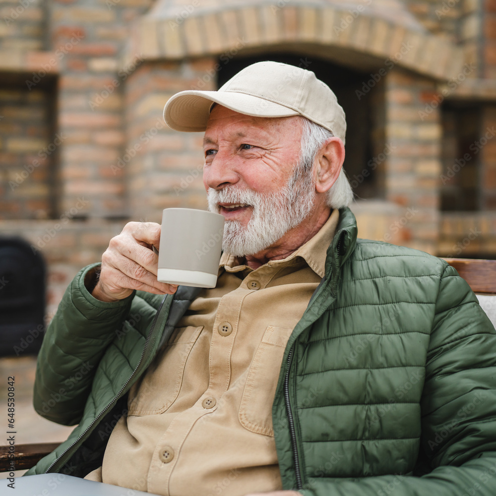 One senior man sit outdoor in autumn day hold cup of coffee or tea One senior man sit outdoor in autumn day hold cup of coffee or tea