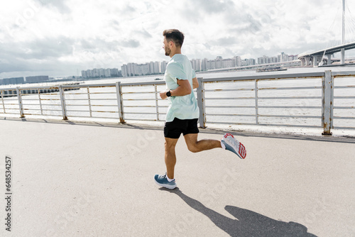 A smart watch for fitness, an athlete uses a mobile app and running shoes. A person is an intensive trainer training in the city. Motivation and mental health of an athlete. 