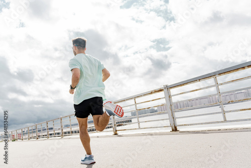 An athlete running in sportswear jogging. Psychological therapy. Man smiles exercise fitness for health. Warm-up man confident interval training.