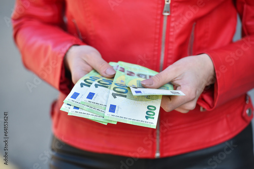 young woman count 100 euro banknotes on the street