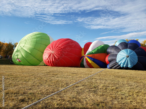Fotografi Several colorful and vibrant hot air balloons lying on the ground while being inflated