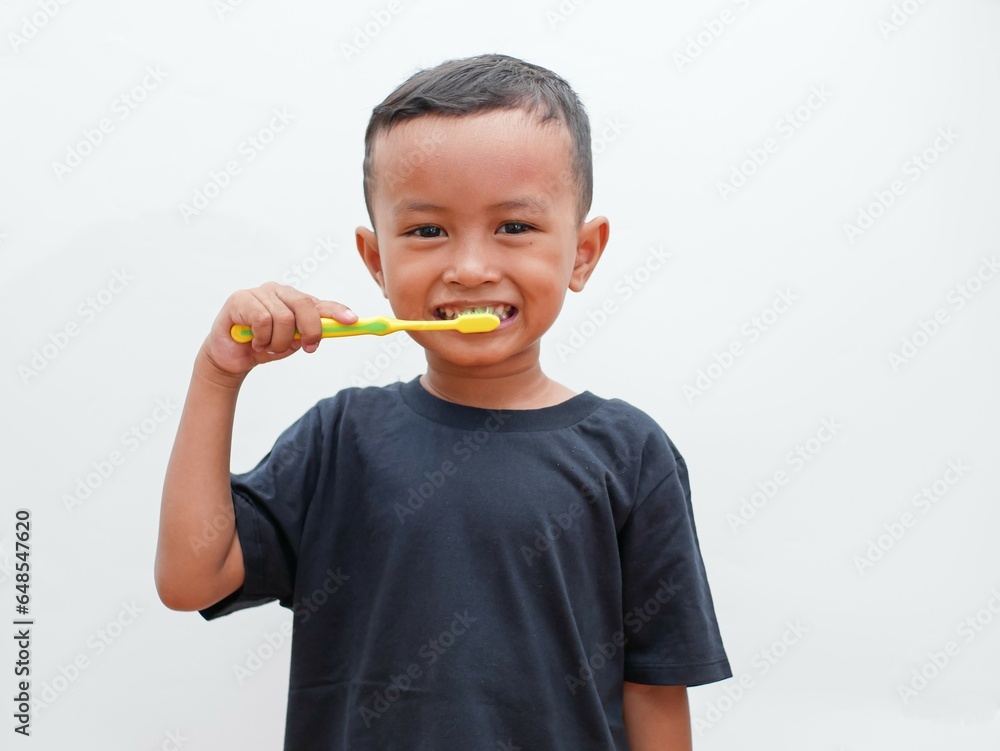 little asian boy brushing his teeth while smiling on white background with copy space. children's dental health concept little asian boy brushing his teeth while smiling on white background with copy space. children's dental health concept
