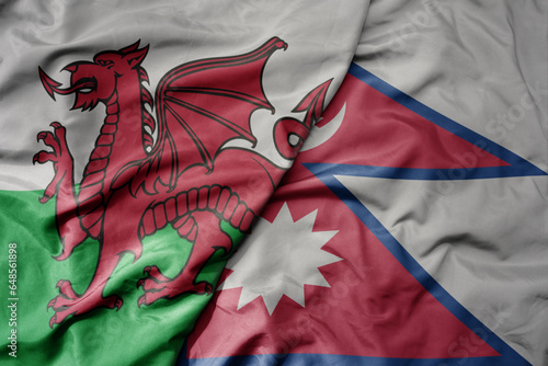big waving national colorful flag of wales and national flag of nepal .