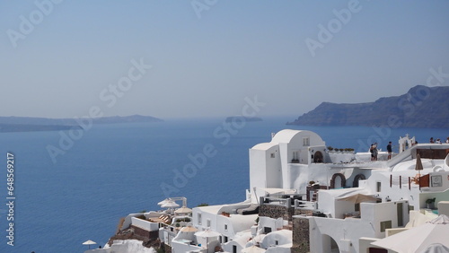 Beautiful Oia town on Santorini island, Greece. Traditional white architecture  and greek orthodox churches with blue domes over the Caldera, Aegean sea. Scenic travel background. photo