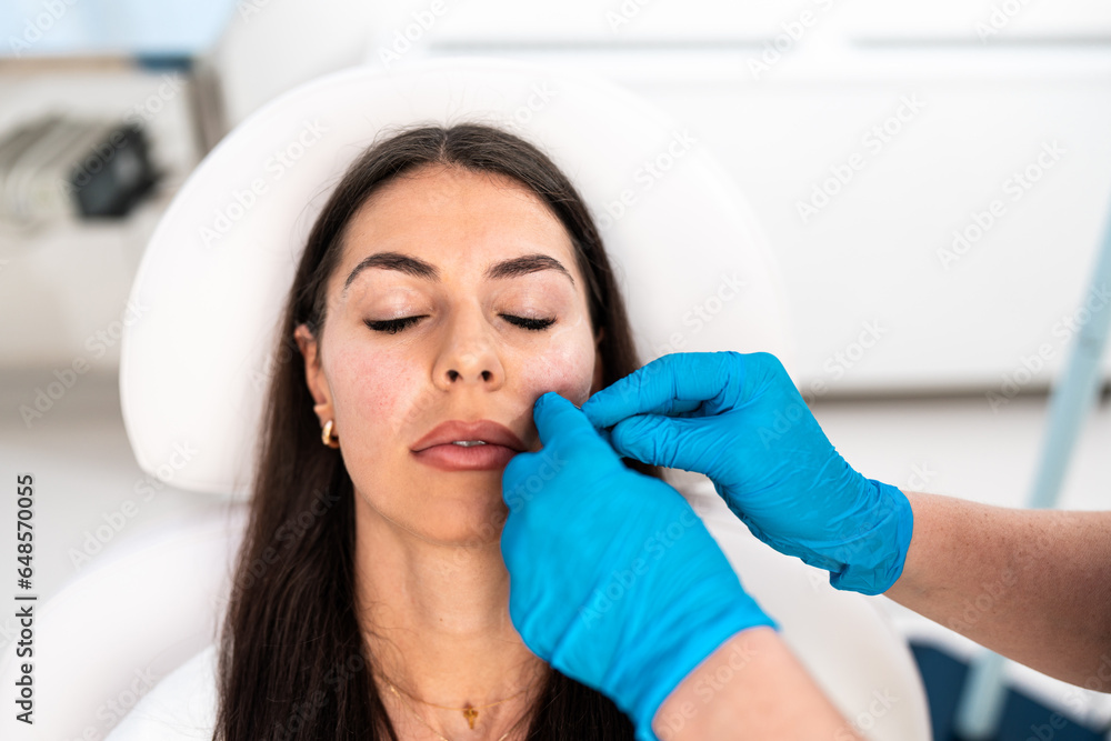 Beautician is contouring the woman's cheekbones with hyaluronic acid