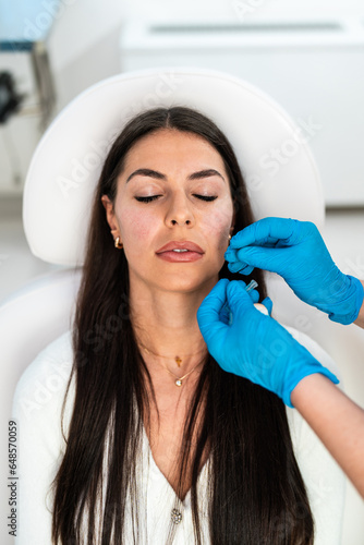 Beautician is contouring the woman's cheekbones with hyaluronic acid filler. Hyaluronic acid filler is injected by needle or cannula. Face contouring concept.