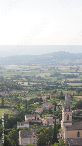 Stunning view of wineyards and farmlands with small villages on the horizon. Summer rural landscape of rolling hills, curved roads and cypresses of Provence, France.