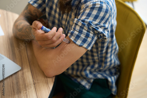 Man in a plaid shirt injects himself into his arm