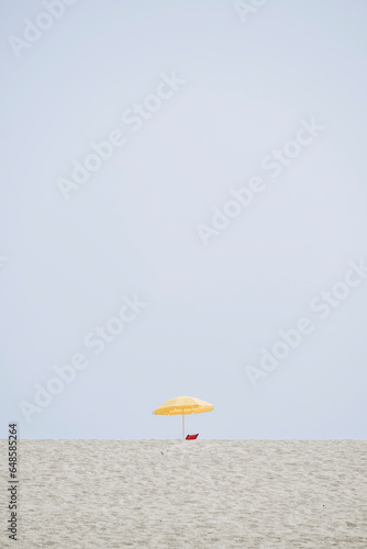 Décor minimaliste avec la plage et un parasol jaune par un jour de ciel bleu