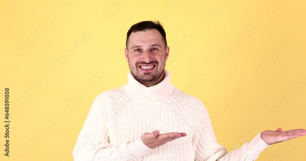 Handsome man presenting something on empty hand with yellow background. Handsome man presenting something on empty hand with yellow background.