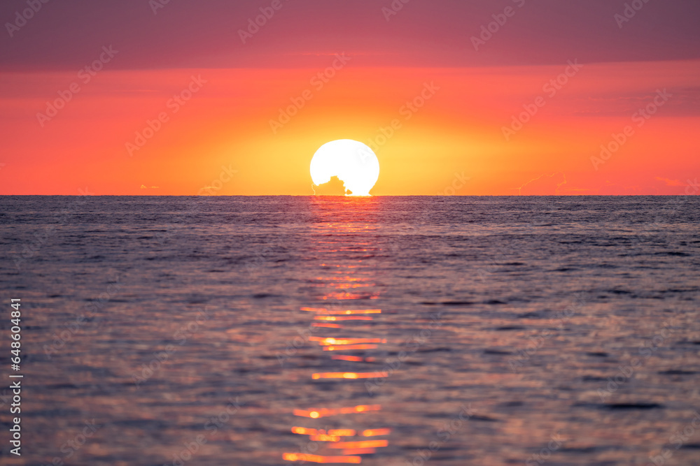 The red sun sets in the sea