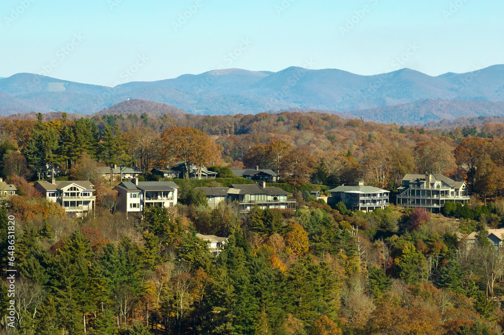 Aerial view of big family houses on mountain top between yellow trees in North Carolina suburban area in fall season. Real estate development in american suburbs Aerial view of big family houses on mountain top between yellow trees in North Carolina suburban area in fall season. Real estate development in american suburbs