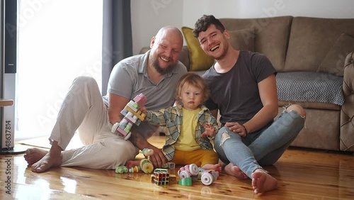 Authentic shot of young happy homosexual male gay family with adopted son toddler baby boyplay together photo
