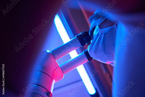 Woman scientist looks through the eyepiece of a powerful microscope photo