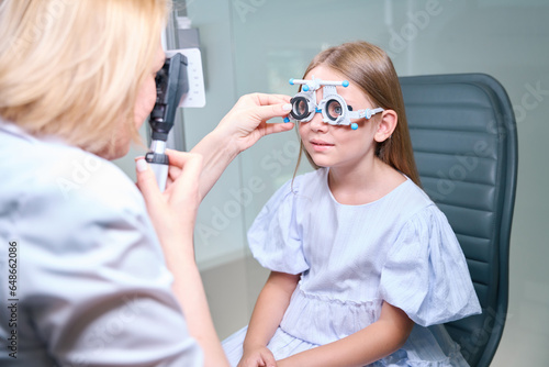 Experienced female optometrist carrying out dynamic retinoscopy on child photo
