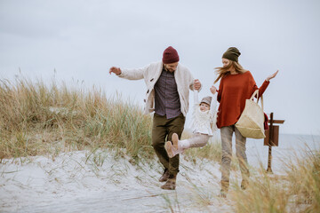 Happy young caucasian couple having fun and walking on a sandy beach during winter