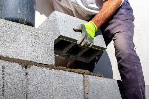 A builder lays an aerated concrete block on a wall photo