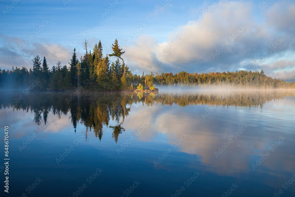 Small island with trees on a foggy northern Minnesota lake at sunrise in September