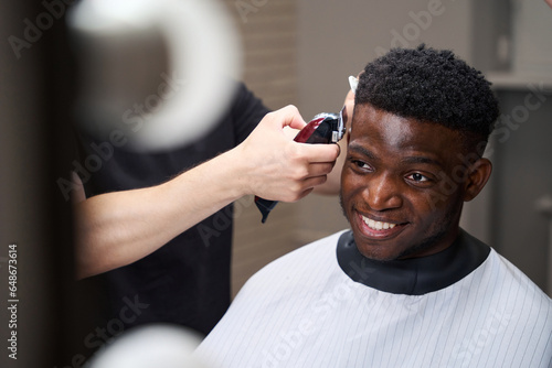 Smiling African American guy sits in a hairdressers chair