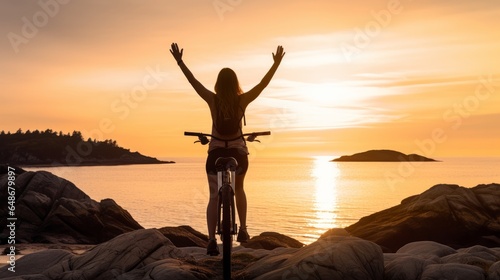 Female cyclist hands free cycling riding bicycle with arms outstretched within the coasts dawn