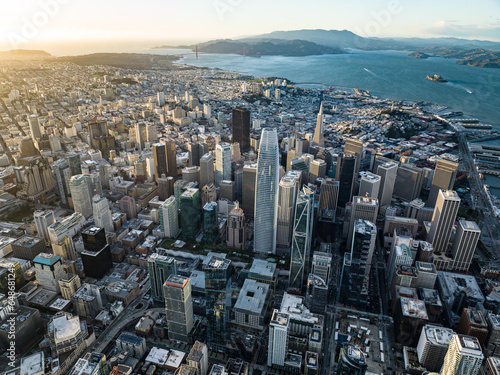 Aerial view of downtown skyscrapers at sunset. Sea bay with islands and hilly landscape in background. San Francisco, California, USA