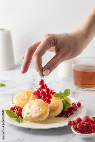 Cottage cheese pancakes, syrniki, ricotta fritters with fresh berries and sour cream on white marble background. Healthy and delicious breakfast, high key
