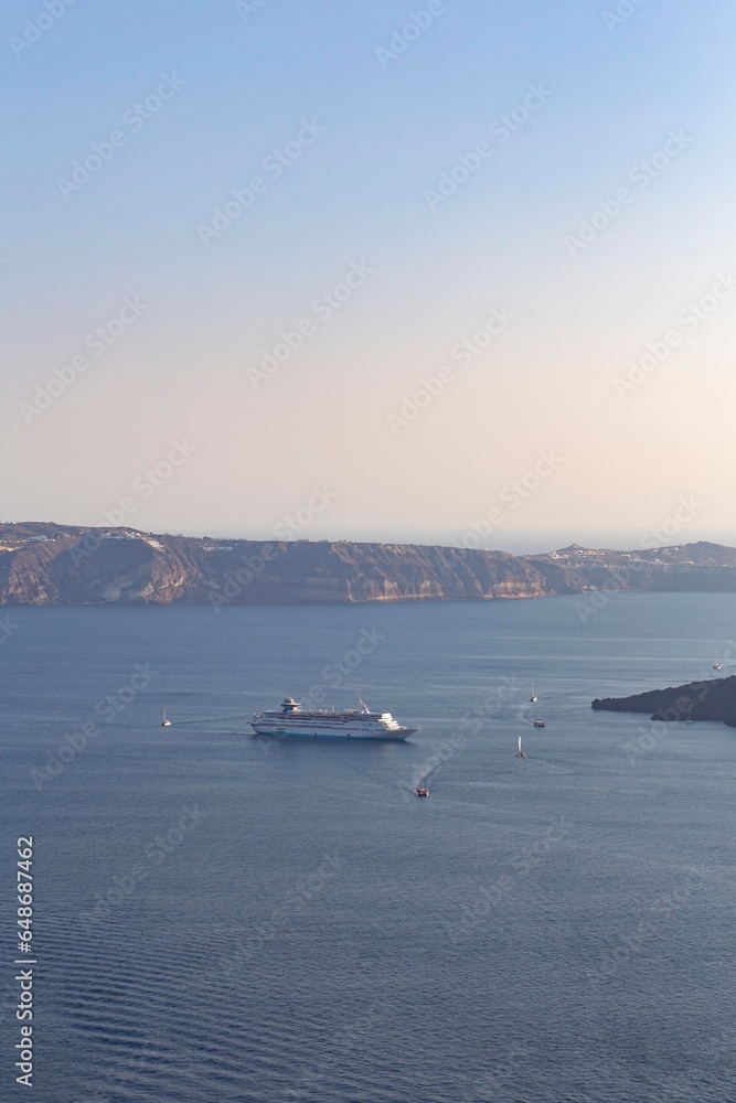 Cruise boat sailing in the shore of the volcanic island of Santorini in Greek Island in the Mediterranean Sea in a summer holidays scene