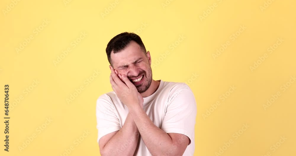 Young man touching sore cheek suffering from toothache on yellow background. Young man touching sore cheek suffering from toothache on yellow background.