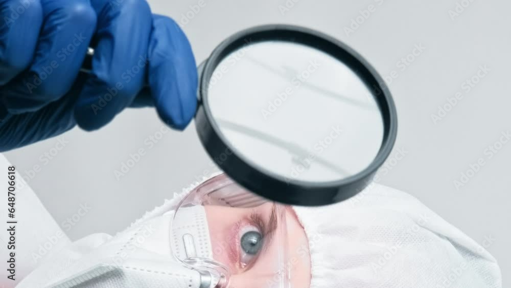 Vertical video. Virology research. Medical examination. Woman doctor laboratory specialist in protective suit equipment with loupe isolated on grey background. Vertical video. Virology research. Medical examination. Woman doctor laboratory specialist in protective suit equipment with loupe isolated on grey background.