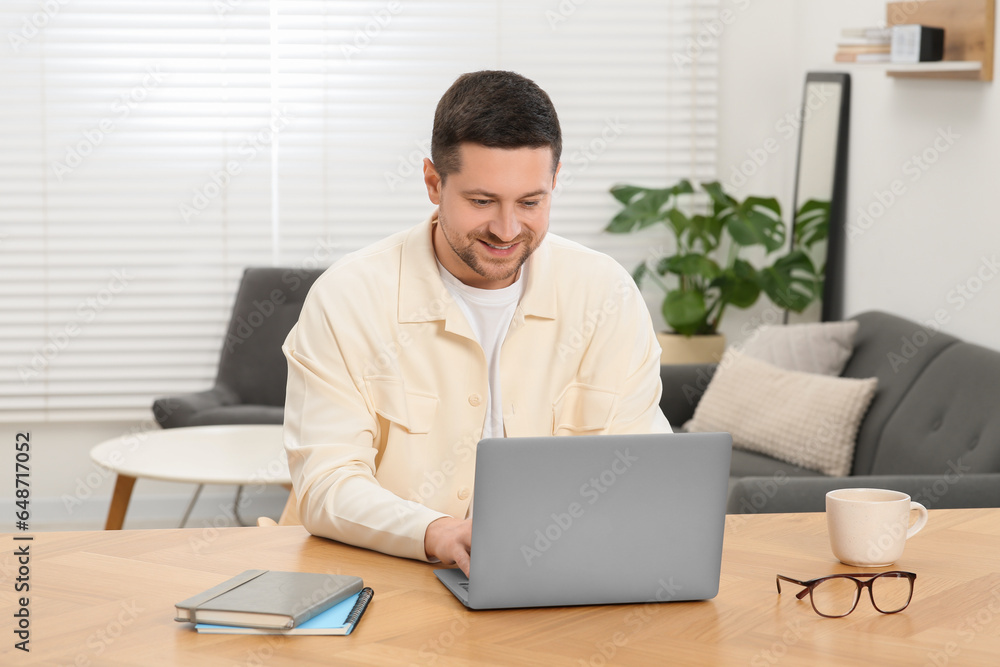 Man working with laptop at wooden table at home Man working with laptop at wooden table at home