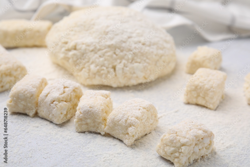 Making lazy dumplings. Raw dough and flour on white tiled table, closeup