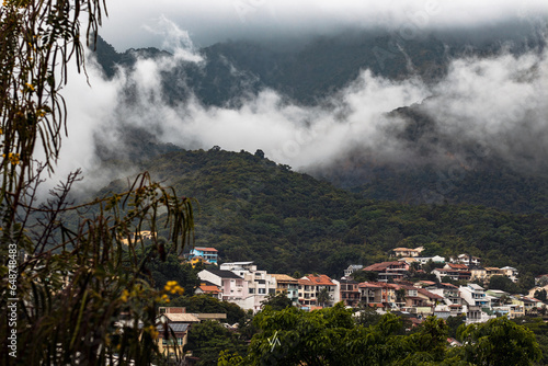 Nuvens no morro, dia frio, neblina, com casas da cidade abaixo