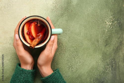 Photographie Woman holding cup of hot mulled wine with apple and pomegranate on grunge backgr