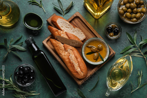 Bowls and different glassware of fresh oil, olives and bread on green background © Pixel-Shot