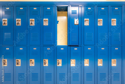 Single open empty blue metal locker along a nondescript hallway in a typical US High School. No identifiable information included and nobody in the hall.	 photo