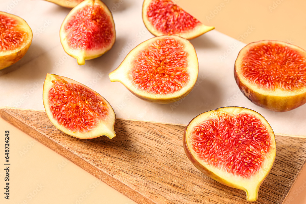 Wooden board with slices of ripe fresh figs on orange background Wooden board with slices of ripe fresh figs on orange background