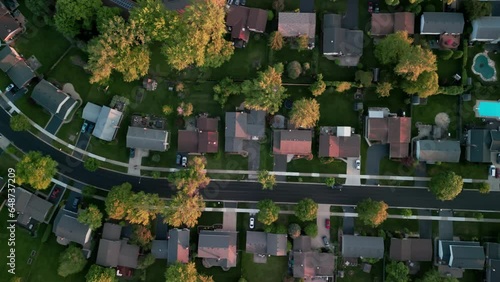 Above top aerial view of colorful trees, residential houses and yards near city . Wide shot footage photo