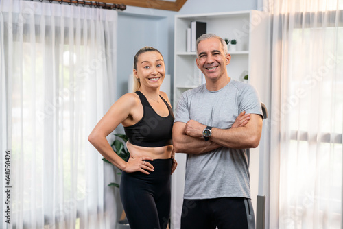 Athletic and sporty senior couple portrait in sportswear with standing posture as home exercise concept. Healthy fit body lifestyle after retirement. Clout