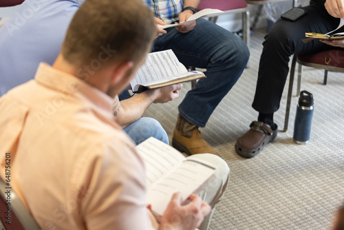 Selective focus on discussion questions in man's hands during men's Bible study during Sunday school at church, young men, young adults, young professionals
