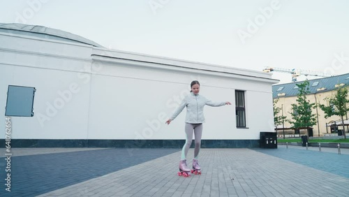 Tracking shot of young woman riding quad rollers skates in city photo