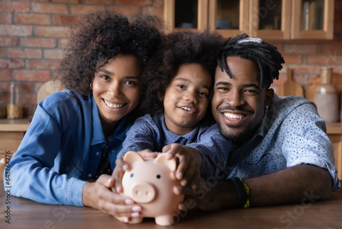 Foto Head shot portrait happy African American family holding piggy bank, looking at