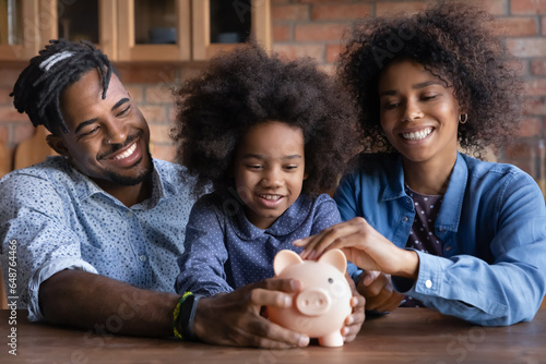 Bilde på lerret Happy African American family with child holding pink piggy bank, sitting at woo