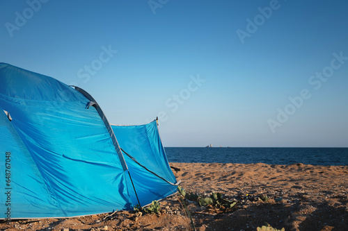 Tent on the sandy beach by the sea. Nobody. A colorful tent to protect from the wind, the sun and to sleep in