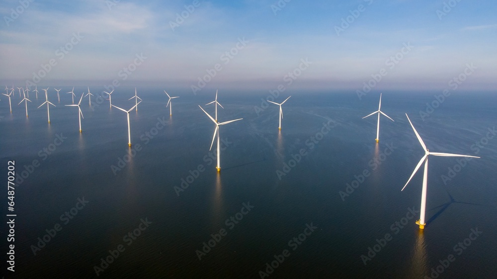 Windmill park in the ocean, drone aerial view of windmill turbines generating green energy electric, windmills isolated at sea in the Netherlands Windmill park in the ocean, drone aerial view of windmill turbines generating green energy electric, windmills isolated at sea in the Netherlands