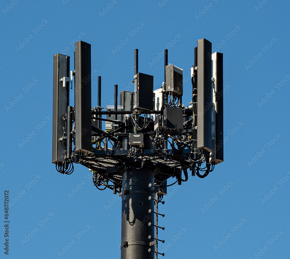 Close up view of a black mobile telecommunication cell tower on a blue sky background 