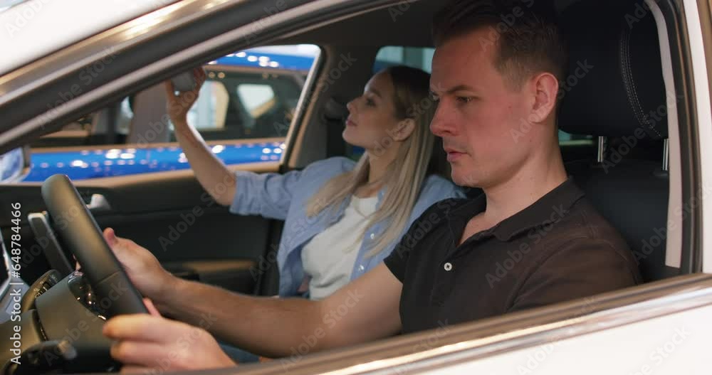 couple in love buying new car in car dealership Happy people hugging sitting inside car Slow motion Excited customers share positive emotions as they have bought vehicle. Girl thanking guy for couple in love buying new car in car dealership Happy people hugging sitting inside car Slow motion Excited customers share positive emotions as they have bought vehicle. Girl thanking guy for