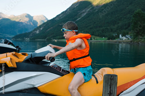 boy sat on a jet ski waiting to go out in a Norwegian Fjord photo