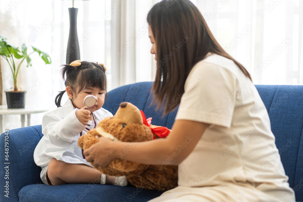 Portrait of enjoy happy love asian family mother and little asian girl smiling activity learn and skill brain training play with costume doctor toy examining heartbeat of teddy bear at home Portrait of enjoy happy love asian family mother and little asian girl smiling activity learn and skill brain training play with costume doctor toy examining heartbeat of teddy bear at home