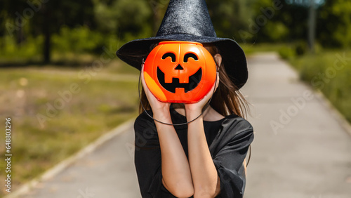 Closeup of unrecognizable little girl wearing Halloween costume and holding pumpkin basket in trick or treat season