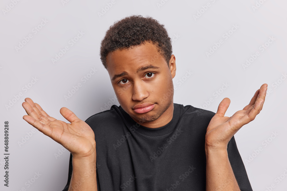 Decision making. Hesitant clueless African man spreads palms feels unaware and confused conveys sense of indecision as if being torn between different choices or unsure about next step to take Decision making. Hesitant clueless African man spreads palms feels unaware and confused conveys sense of indecision as if being torn between different choices or unsure about next step to take